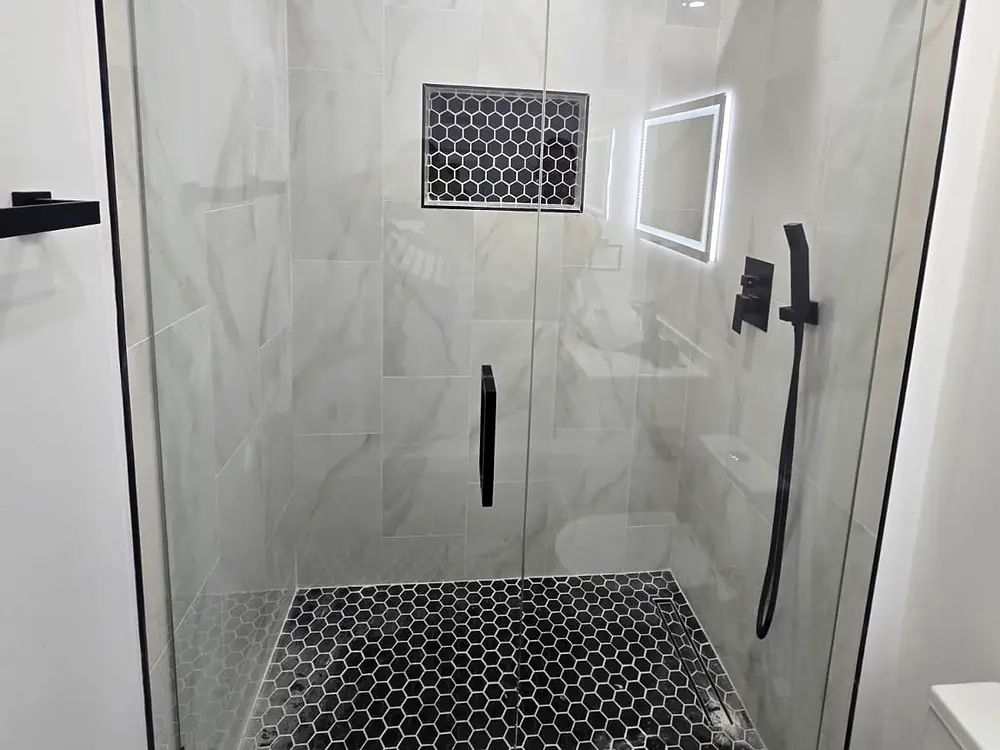 Ducha terminada con cerámica tipo mármol y puerta de vidrio