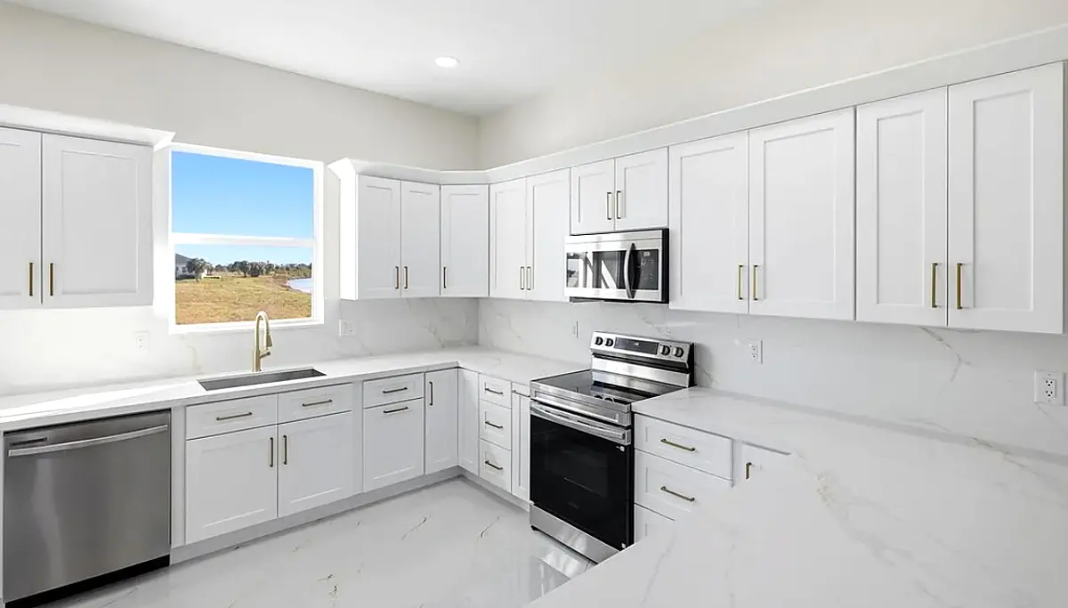 White shaker kitchen with quartz counters and gold hardware
